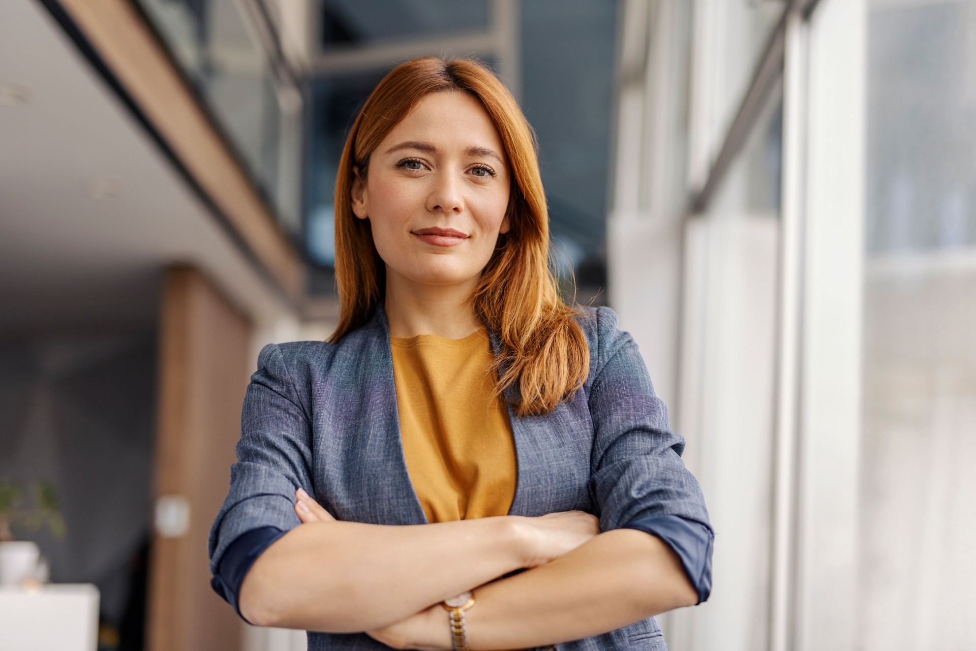 Close up of confident successful businesswoman standing at corporation with arms crossed and looking at camera.